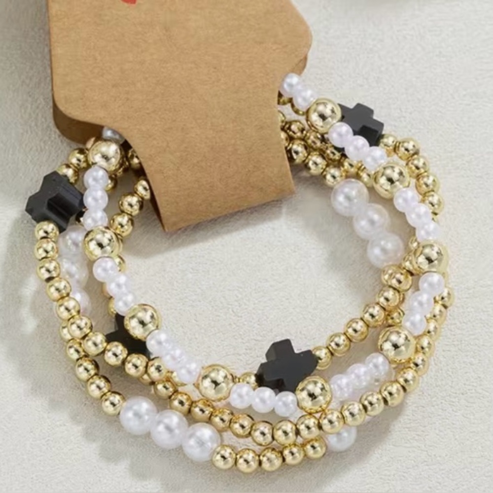 Set of 4 stretch bracelets.gold, pearl and black cross
